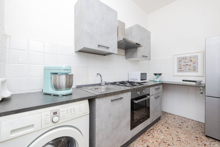 Modern kitchen with stainless steel appliances, gas cooktop, white cabinets, and light blue stand mixer on counter